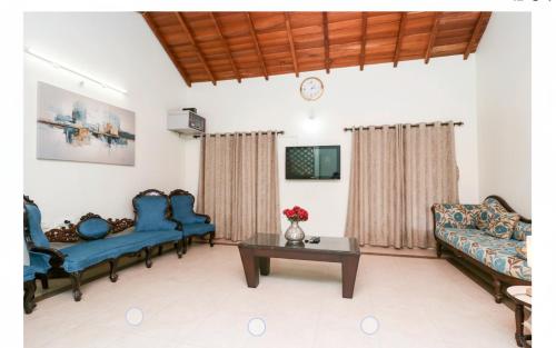 ein Wohnzimmer mit blauen Sofas und einem Tisch in der Unterkunft Coffee cottage guest house in Madikeri