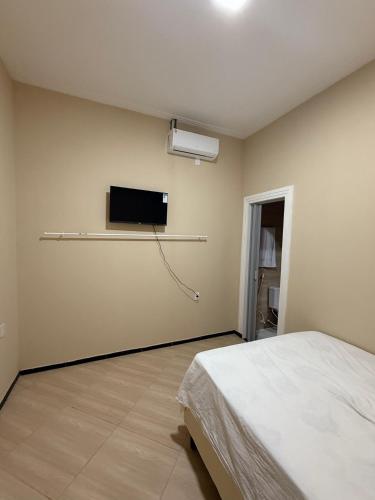 a bedroom with a bed and a tv on the wall at Garrida in Itarema