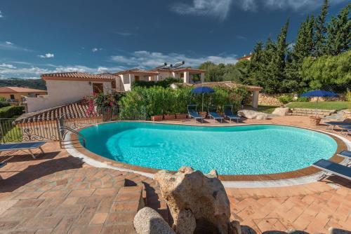 Una piscina en un patio con sillas y sombrillas. en Stunning Residence Bouganvillage 2 Bed Apt sleep 6, en Tanaunella
