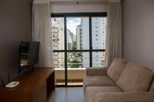 a living room with a couch and a large window at BHomy Madison in Sao Paulo