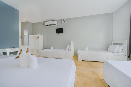a white room with two beds and a tv at Casa Cecilia in El Nido