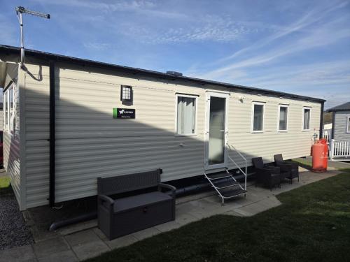 a large white trailer with a porch and a staircase at zucolli's Caravan at Trecco Bay Holiday Park in Porthcawl