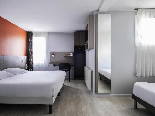 a hotel room with two beds and a mirror at greet Hotel Massieux Lyon Nord in Massieux