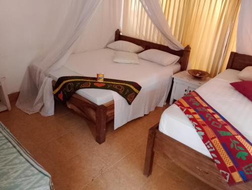 a bedroom with two beds and a table and a bedskirts at fulles guest house in Gili Trawangan