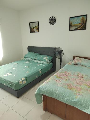 a bedroom with two twin beds and a fan at Homestay Qaseh Ibu sungai petani in Sungai Petani