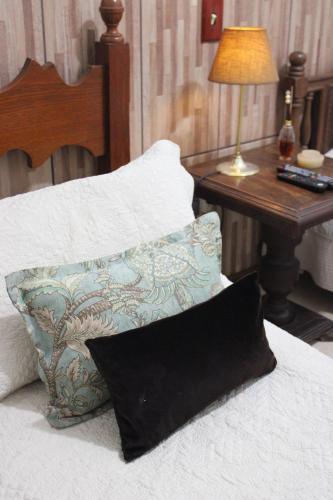 a bed with a pillow and a table with a lamp at Pousada do Campo in Barra do Piraí