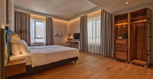 a bedroom with a bed and a desk and a television at voco The Hague by IHG in The Hague