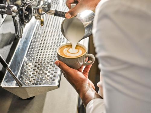 a man is making a coffee in a cup at voco The Hague by IHG in The Hague