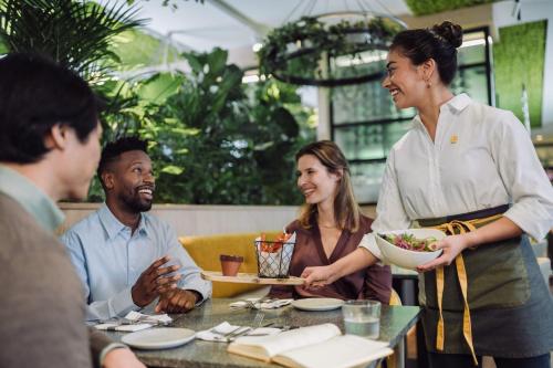 a woman holding a bowl of food in a restaurant at voco The Hague by IHG in The Hague