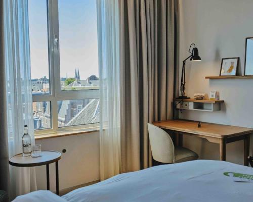 a hotel room with a desk and a window at voco The Hague by IHG in The Hague