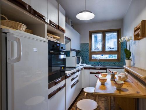 a kitchen with a wooden table and a white refrigerator at Grand appart familial 3 pièces près centre et pistes avec wifi - FR-1-575-161 in Courchevel