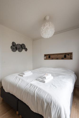 a white bed with two towels on it in a room at Seaview Penthouse with Terrace Nieuwpoort in Nieuwpoort