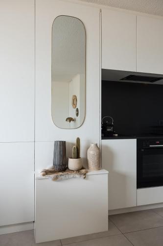a kitchen with white cabinets and a mirror at Seaview Penthouse with Terrace Nieuwpoort in Nieuwpoort