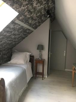 a attic room with a bed and a ceiling at Le Logis Fleurs et jardins de Pitry in Thierville