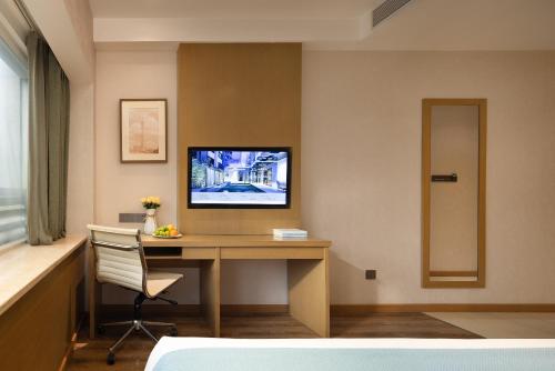 a room with a desk and a tv on a wall at True Go Hotel - Guangzhou International Conference Center Memorial Hall Subway Station in Guangzhou