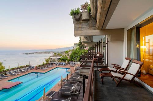 a hotel balcony with a pool and chairs at Eurostars Monte Tauro in Taormina