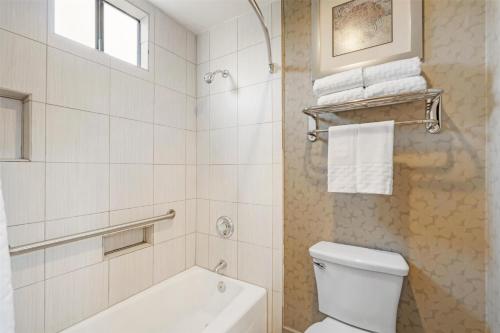 a white bathroom with a toilet and a bath tub at Best Western Plus Anaheim Inn in Anaheim