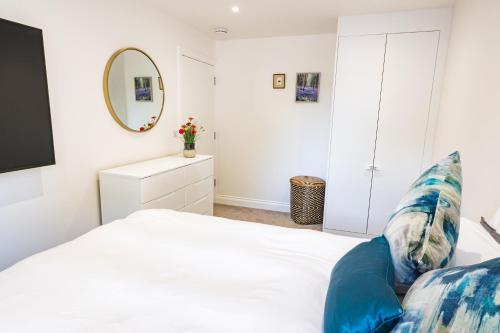 a bedroom with a white bed and a mirror at Stylish flat in the heart of Hitchin with free parking in Hitchin