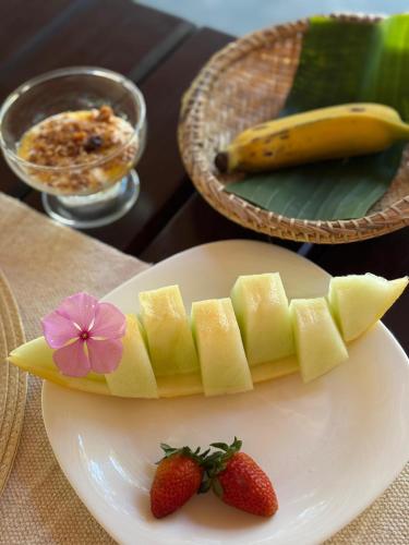 a plate with a sliced banana and strawberries on a table at Pousada Arraial dos Sonhos in Arraial d'Ajuda