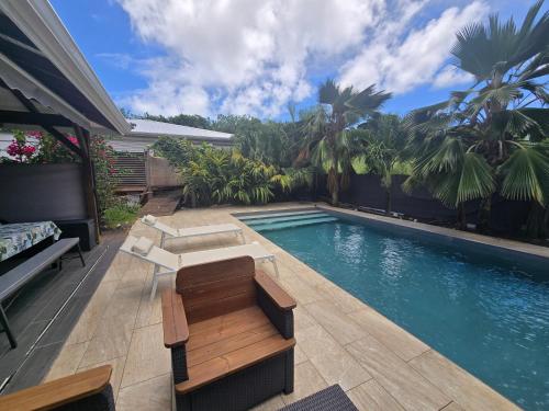 a swimming pool with a bench next to a house at Magnifique maison en bois avec piscine in Sainte-Anne