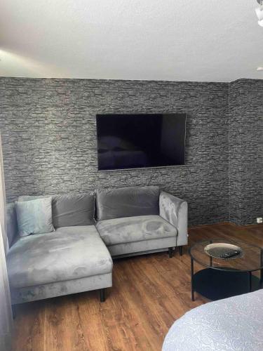 a living room with a couch and a tv on a wall at Sehr gute Lage mit Straßenbahn vor der Tür & riesen Bett, Messe nah in Essen