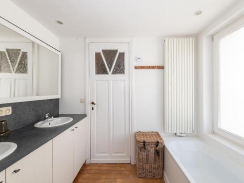 a white bathroom with two sinks and a mirror at Notre Dame in Nieuwpoort