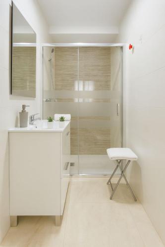 a white bathroom with a shower and a stool at Triana Home centro ciudad in Murcia