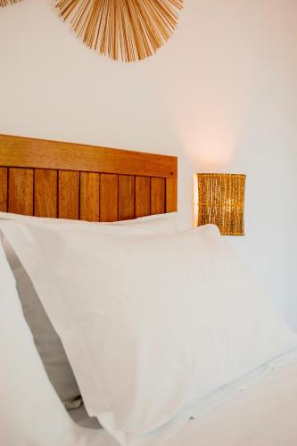 a bedroom with a white bed with a wooden headboard at Pousada Fenícia in Japaratinga