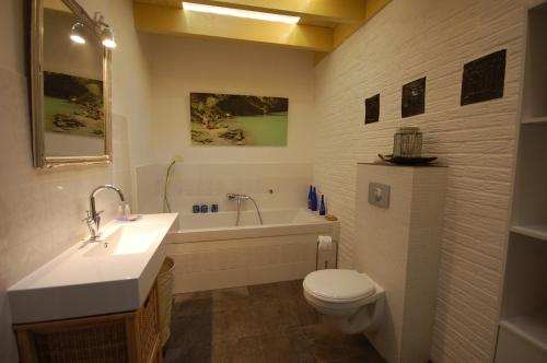 a bathroom with a sink and a toilet and a tub at B&B BeZINspiratie in Schuinesloot