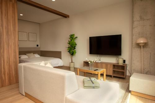 a living room with two beds and a flat screen tv at Comfortable Apartment Near Expo Guadalajara Parking & WiFi in Guadalajara