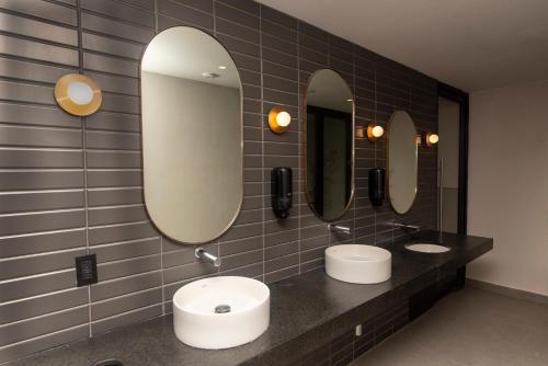 a bathroom with two sinks and two mirrors at Comfortable Apartment Near Expo Guadalajara Parking & WiFi in Guadalajara