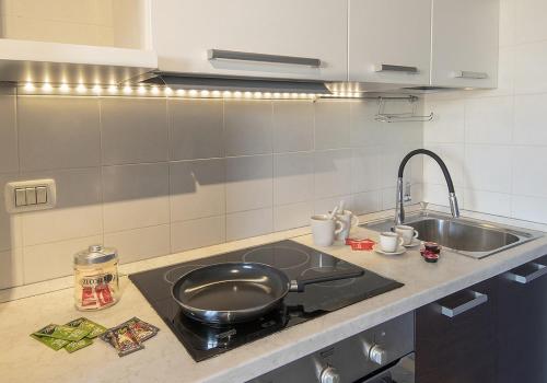 a kitchen with a sink and a frying pan on a stove at New One Bedroom Apartment in Milan 3 minutes from the metro in San Giuliano Milanese
