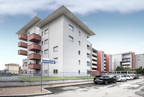 a white building with cars parked in a parking lot at New One Bedroom Apartment in Milan 3 minutes from the metro in San Giuliano Milanese