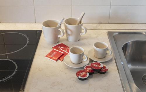 a kitchen counter with three coffee cups and a sink at New One Bedroom Apartment in Milan 3 minutes from the metro in San Giuliano Milanese