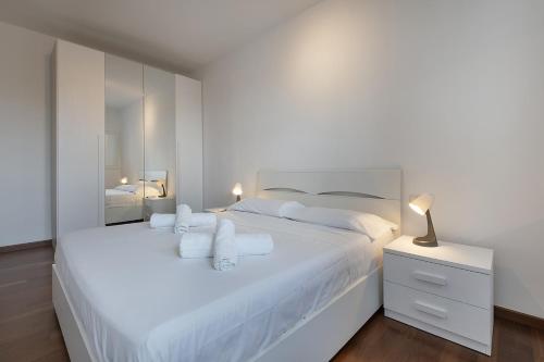 a white bedroom with two white beds and a lamp at New One Bedroom Apartment in Milan 3 minutes from the metro in San Giuliano Milanese