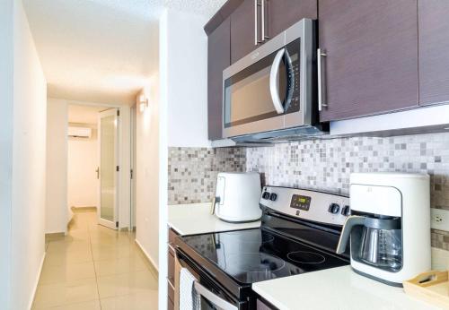 a kitchen with a stove and a microwave at Aquaville Dorado Moderna Villa 1 in Dorado