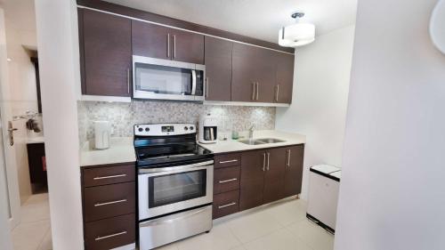 a kitchen with brown cabinets and a stove and microwave at Aquaville Dorado Moderna Villa 1 in Dorado