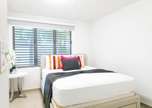 a white bedroom with a bed and a window at Aquaville Dorado Moderna Villa 1 in Dorado
