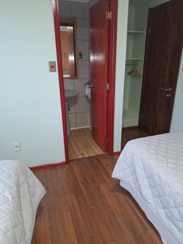 a room with a bedroom with a bed and a bathroom at Asói Hostal in Puerto Natales