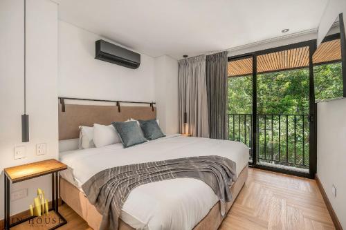 une chambre avec un lit et une grande fenêtre dans l'établissement Morph 201 - High ceilings & modern apt/BBQ, à El Poblado