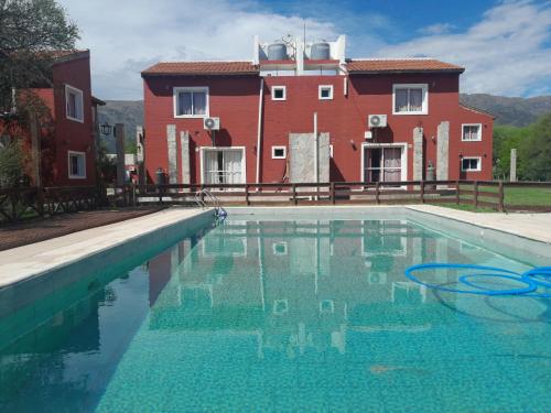 a swimming pool in front of a red building at Alma Apart in Los Molles