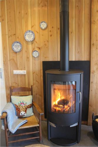 a stove in a room with a chair and a fireplace at B&B 't Bievink - buitengewoon overnachten in Westendorp