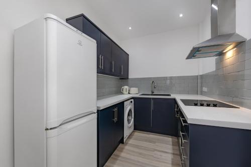 a kitchen with blue cabinets and a white refrigerator at Blue Horizon Seaside Apart in Clacton-on-Sea