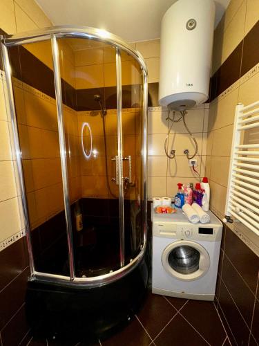 a small bathroom with a shower and a washing machine at Prishtina Sky View in Prishtinë