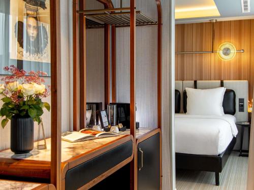 a hotel room with a bed and a desk with a desk sidx sidx at MUZE Hotel Dusseldorf - Handwritten Collection in Düsseldorf