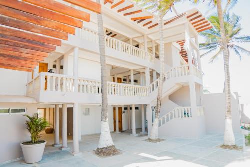 a white house with palm trees in front of it at Hotel Playa Palmeras Cartagena - Vía al Mar in Cartagena de Indias