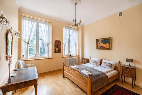 a bedroom with a bed and a table and windows at Cosmo - Old Money Apartment in Gdańsk