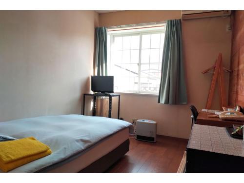 ein Schlafzimmer mit einem Bett, einem Fenster und einem Schreibtisch in der Unterkunft Hotel Park Light - Vacation STAY 39467v in Inai