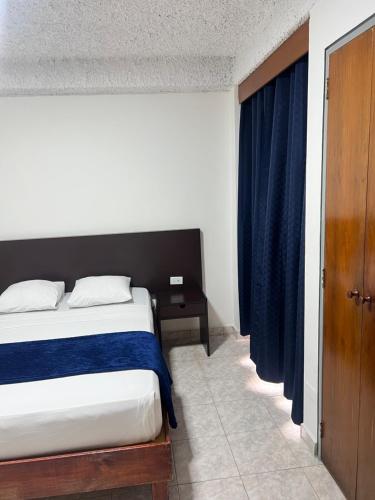 a bedroom with a bed and a blue curtain at Hotel Grand Galaxie in Caracas