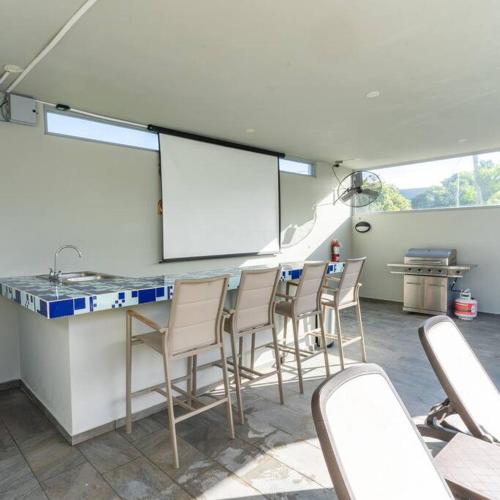 a room with a bar with chairs and a screen at Aquaville Dorado Moderna Villa 3 in Dorado